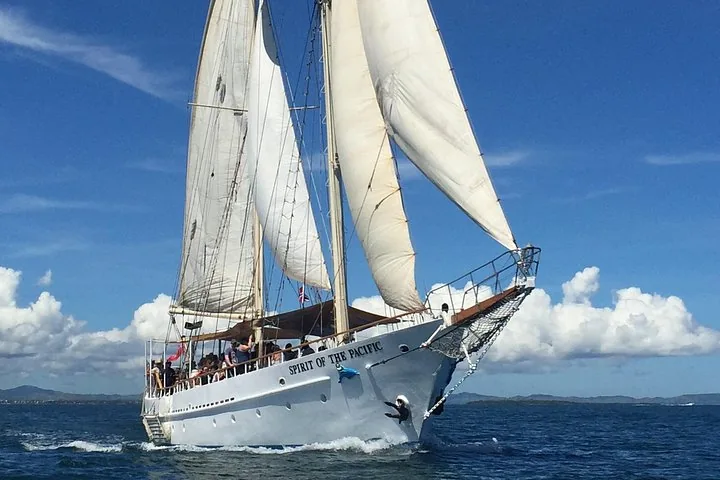 A large white sailboat, Spirit of the Pacific, sailing on blue water.