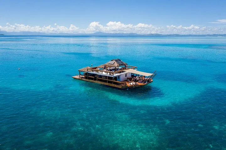 Luftaufnahme einer schwimmenden Bar und eines Restaurants in ruhigem, klarem Wasser.