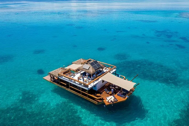 Draufsicht auf einen schwimmenden Loungebereich mit Sonnenliegen und Dächern aus Stroh.