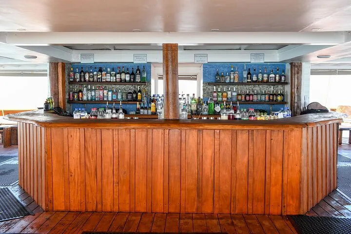 A well-stocked wooden bar counter on a boat or floating platform.